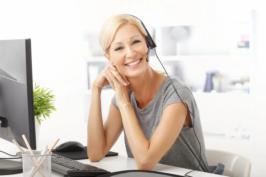 Portrait of a beautiful customer representative with headset smiling during a telephone conversation.